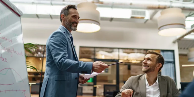 Two men discuss with pen and whiteboard
