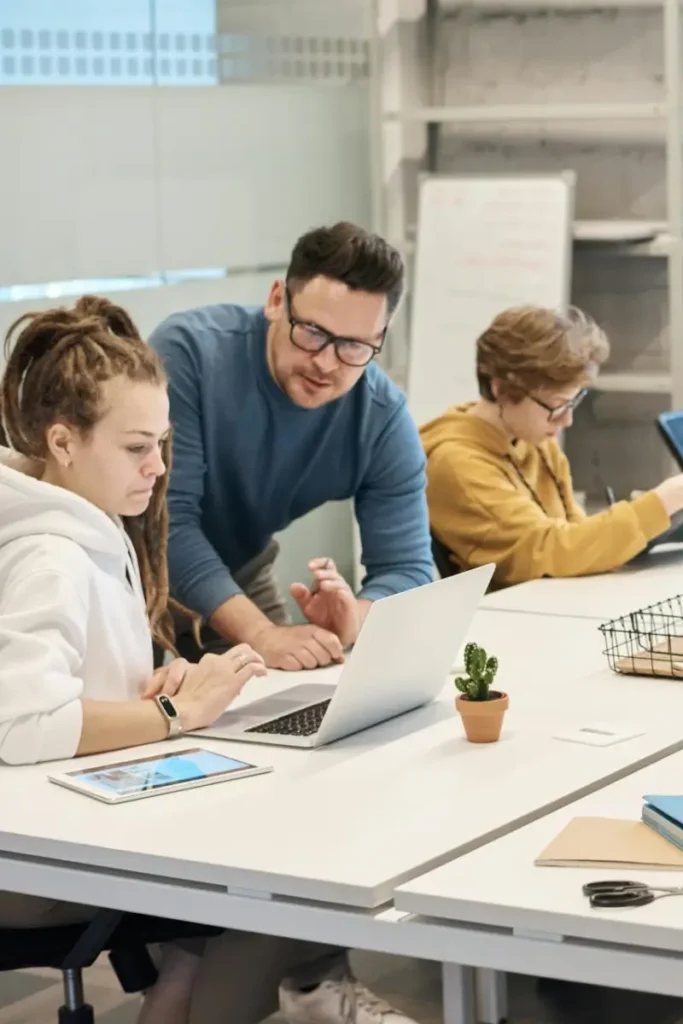 Team members discuss, with laptop and tab